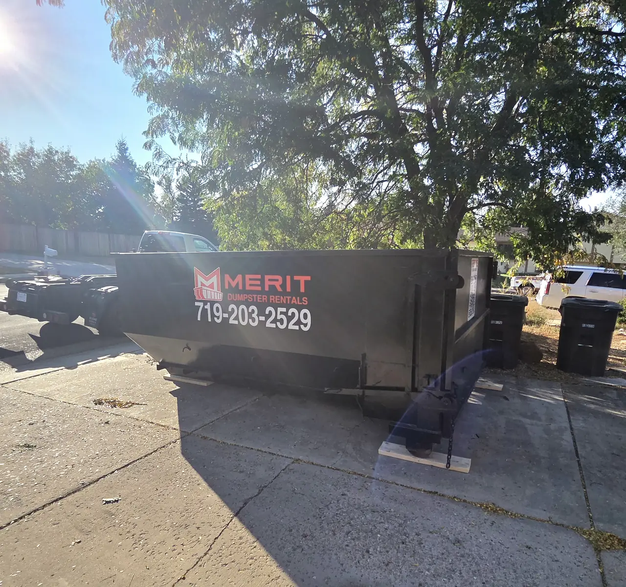 A Merit container set on wood boards on a concrete driveway